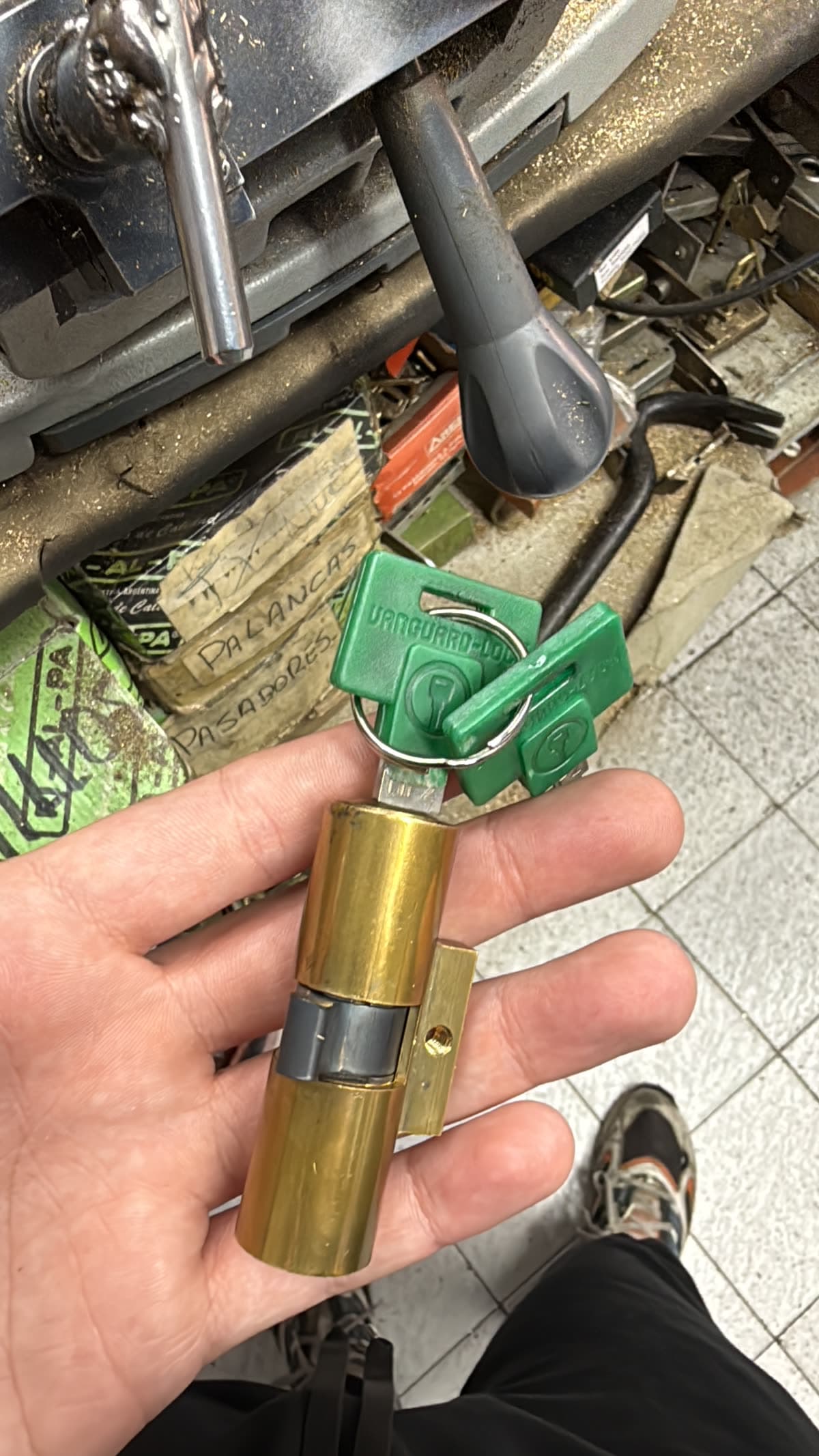 Cilindro Vanguard Lock con dos llaves verdes sostenido en el taller